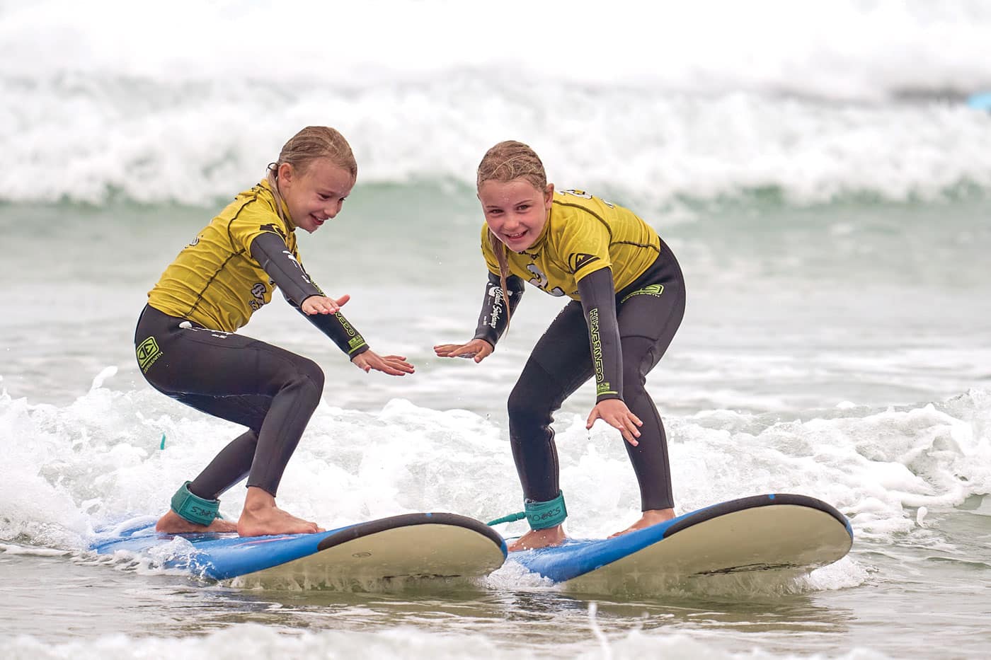 2 blond young girls learning to surf together on  their family holiday