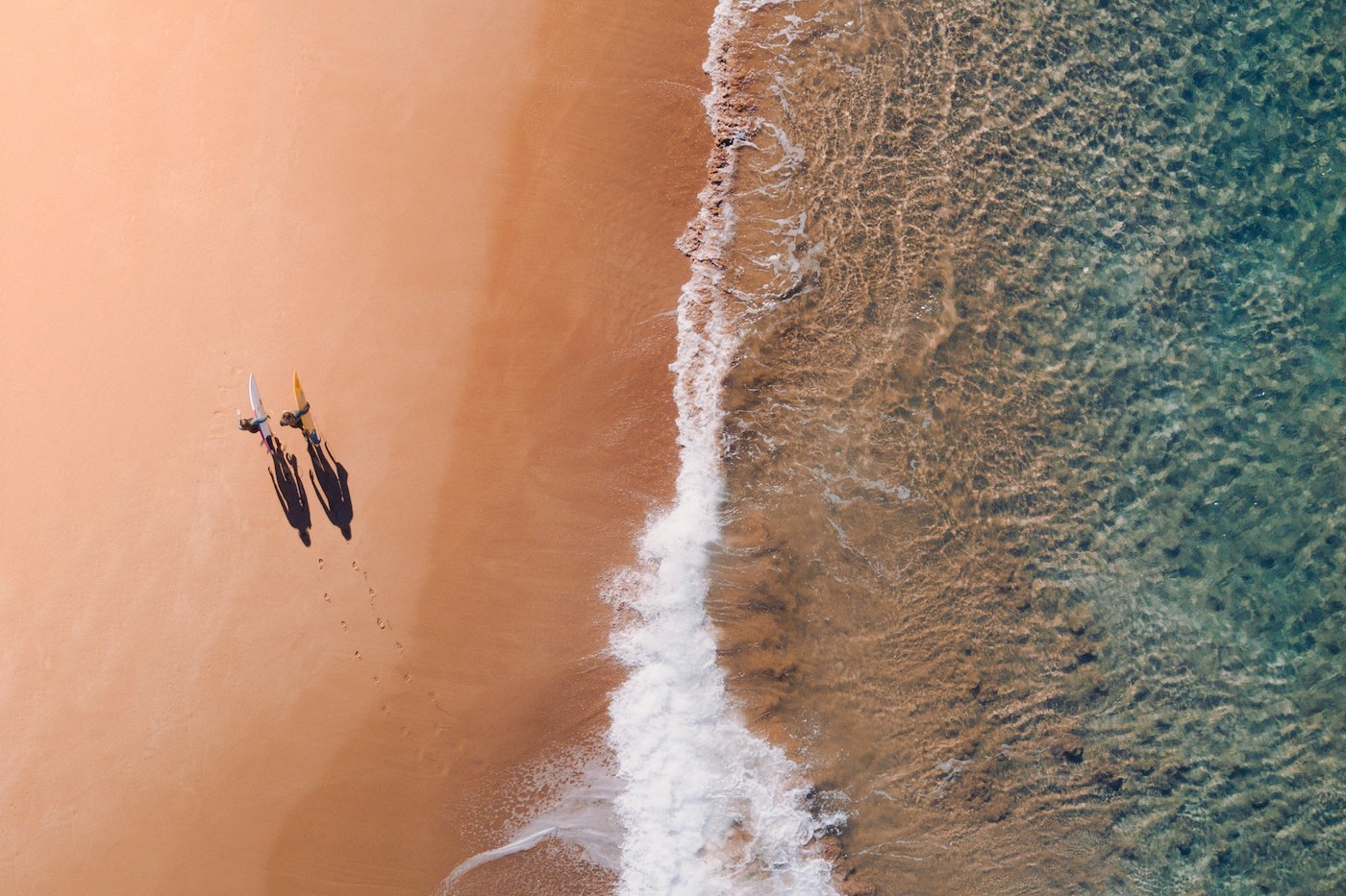 Drone photo of beach and waves breaking on it from above
