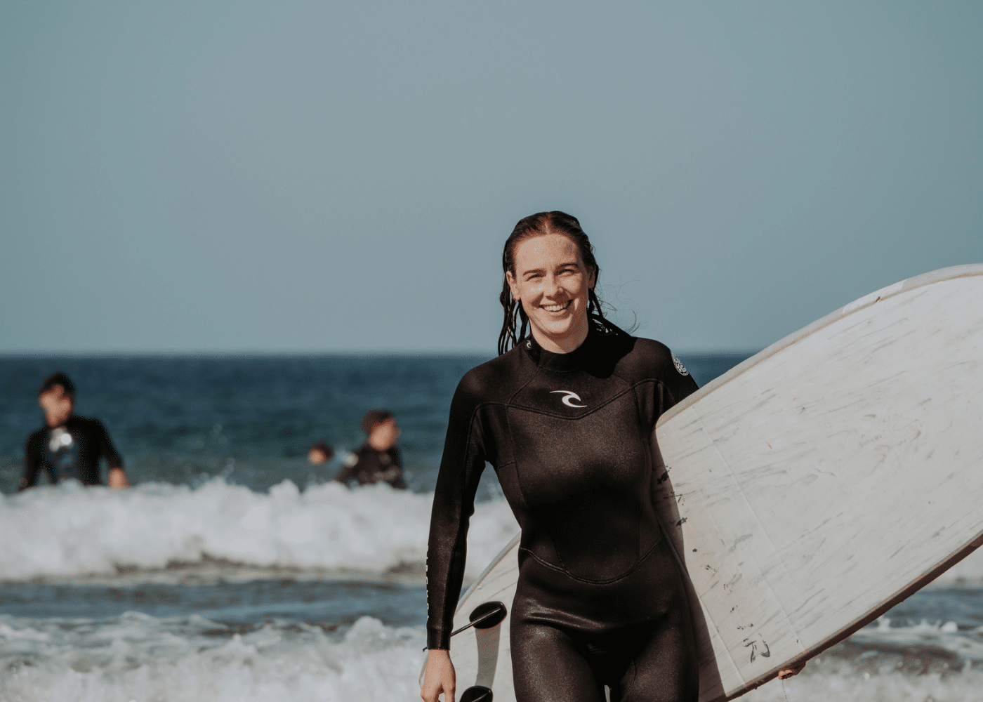 A girl at Amayour Surf & Yoga holding a beginner surfboard