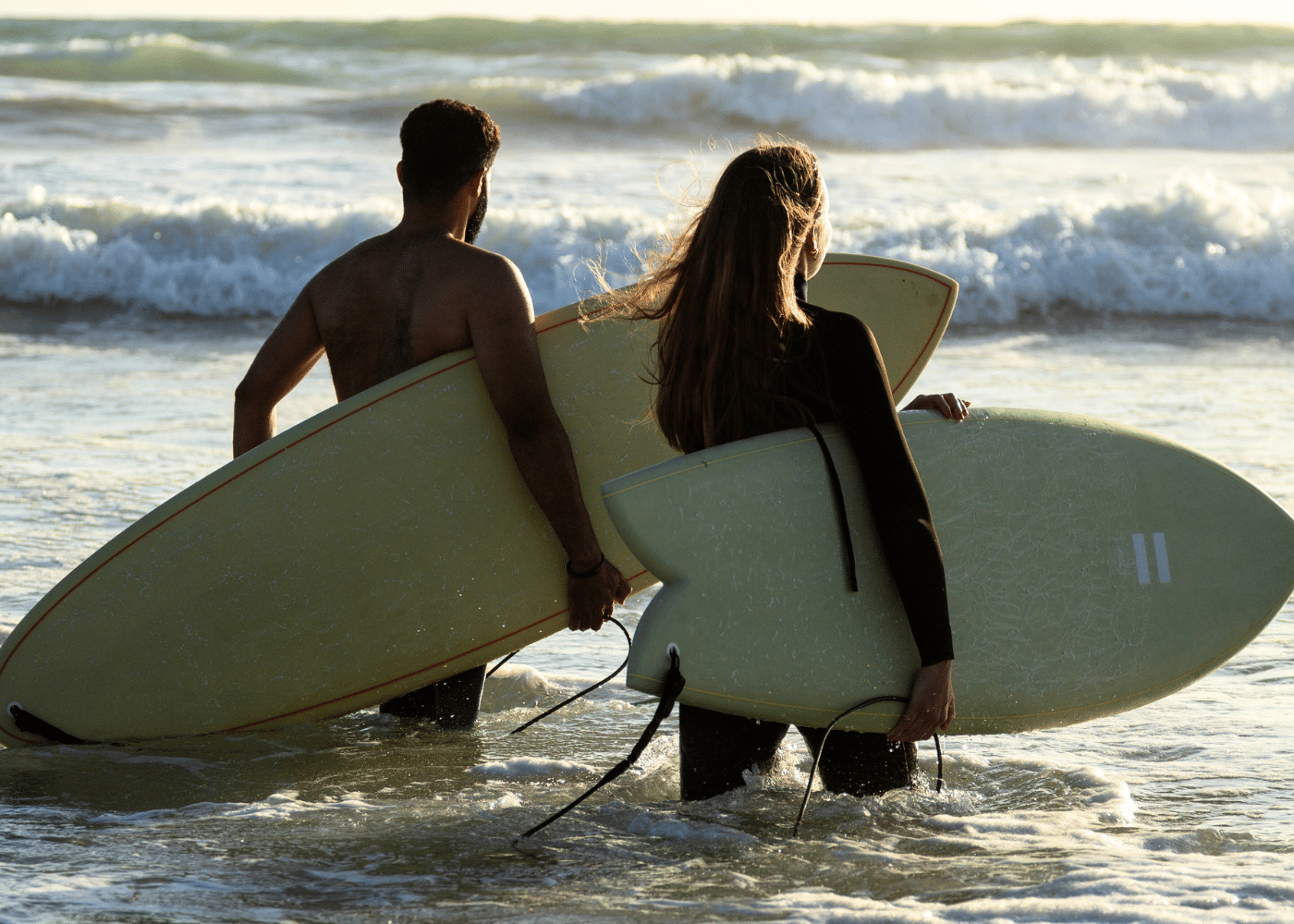 Two people heading out for a surf at Paradis Plage