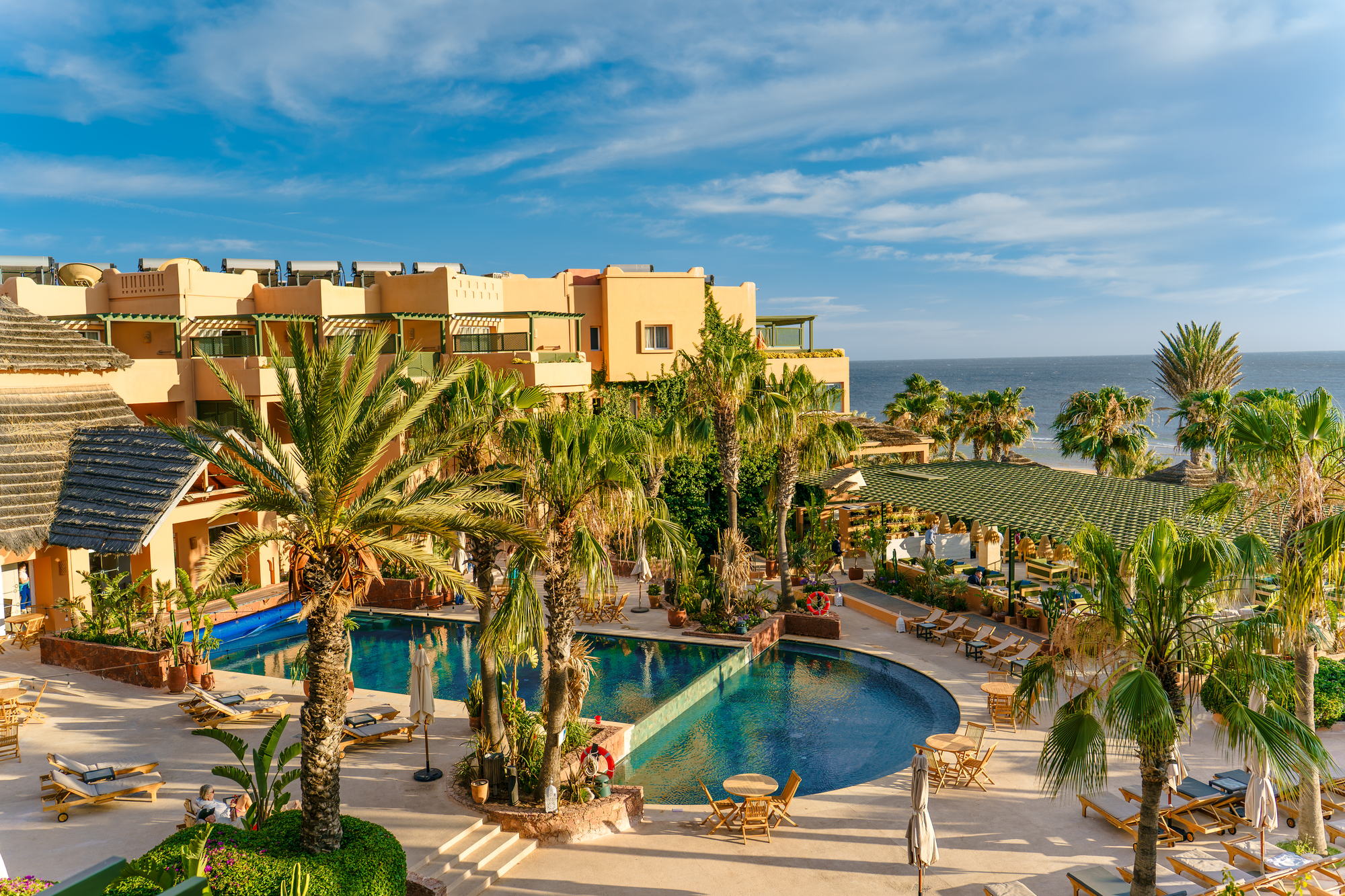 The pool, palms and ocean-facing rooms at Paradis Plage luxury surf resort on the Atlantic coast of Morocco