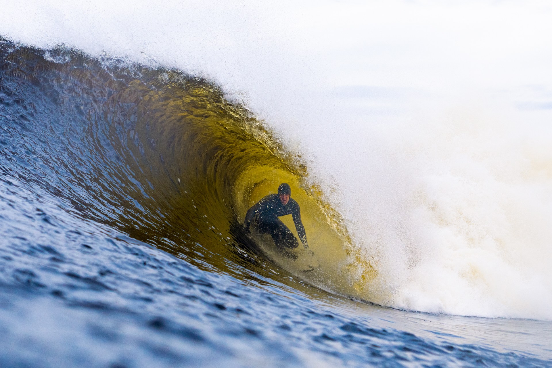 Mark Boyd crouched inside a golden barrel as the lip throws over him