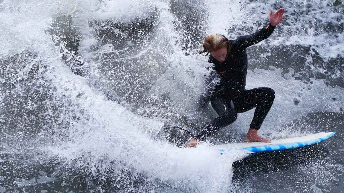 Caity Simmers driving through a turn in heavy spray on a blue and white board