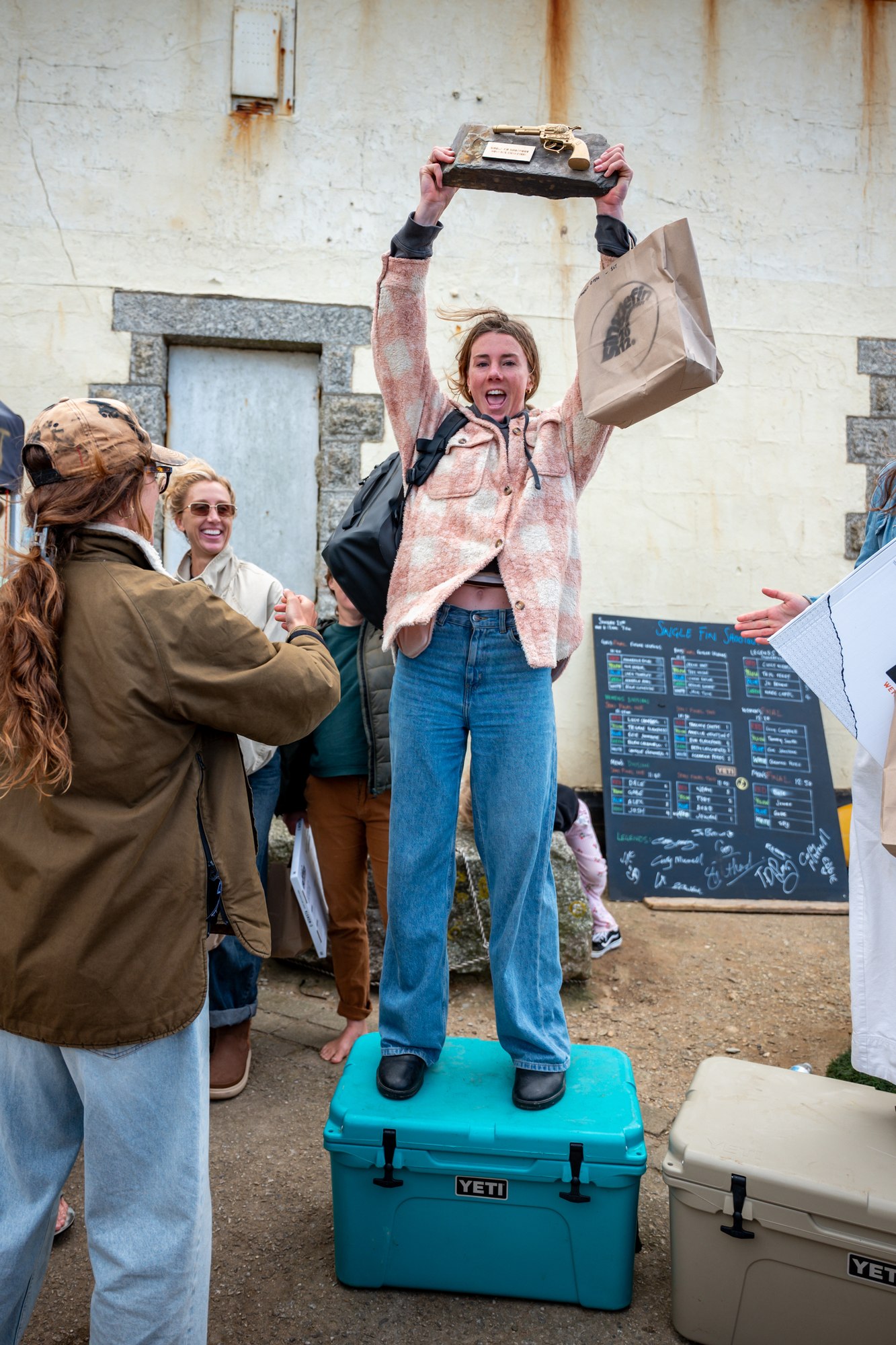 Lucy Campbell standing on a cool box holding the trophy above her head