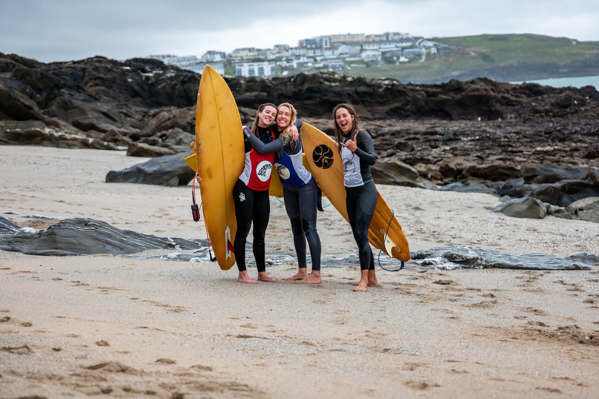 Lucy Campbell with two other competitors holding single fin boards on the beach