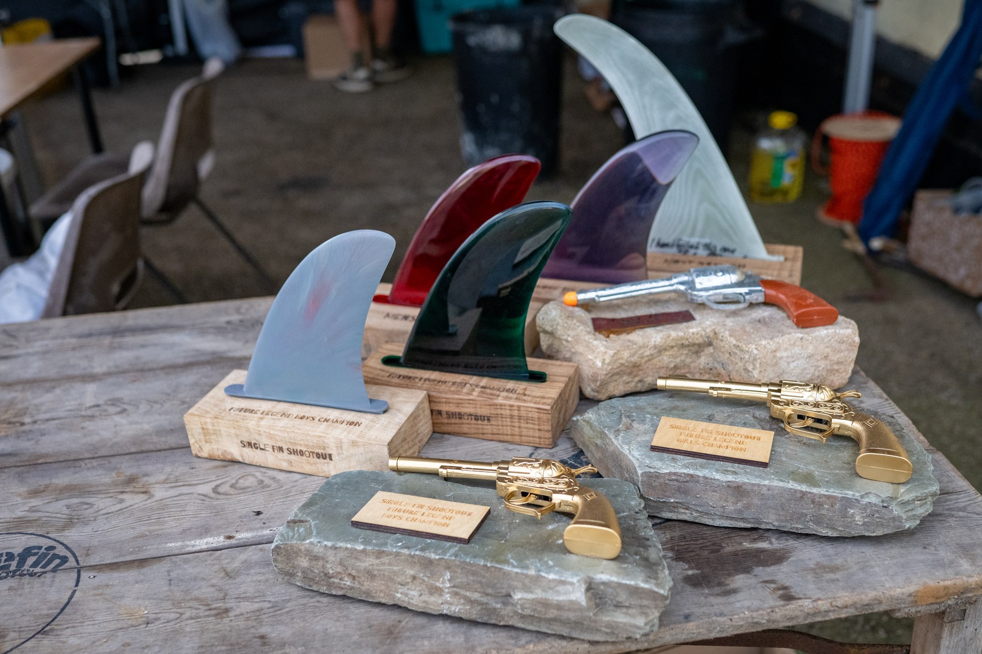 Single Fin Shootout trophies: resin fins on oak bases and gold toy revolvers on slate